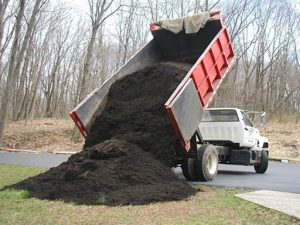 A pile of dirt being poured from a truck